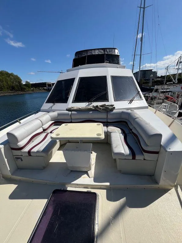 Slide: The Image of 1993 Kha Shing Motoryacht with spacious deck seating and table, docked under clear blue skies. - 15