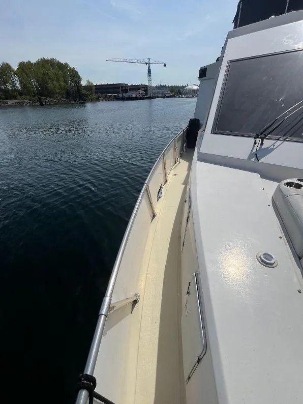 Slide: The Image of 1993 Kha Shing Motoryacht on calm water, with a crane and trees in the background. - 17