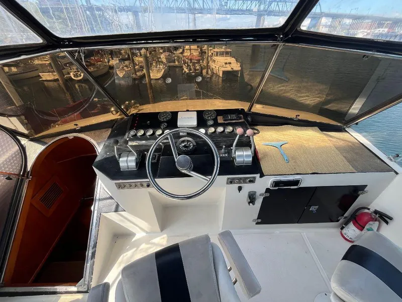 Slide: The Image of 1993 Kha Shing Motoryacht helm with steering wheel, controls, and waterfront view. - 38