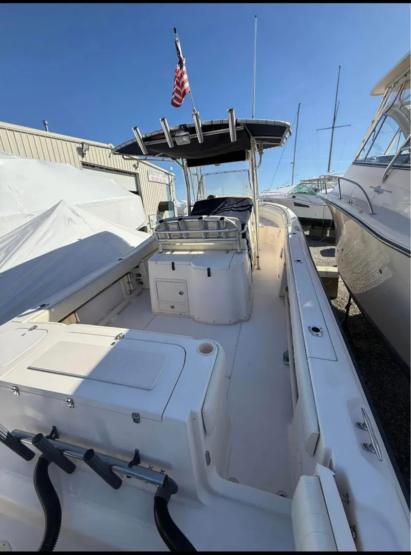 Slide: The Image of 2005 Grady-White Release 283 boat with T-top and American flag, docked between other vessels. - 4