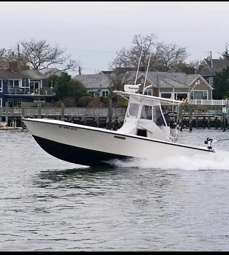 Slide: The Image of 1998 Albemarle 242 Center Console boat cruising on a calm waterfront near houses. - 1