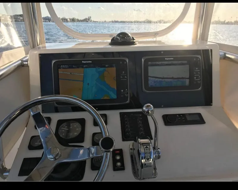 Slide: The Image of 1998 Albemarle 242 Center Console helm with navigation screens and steering wheel at sunset. - 6