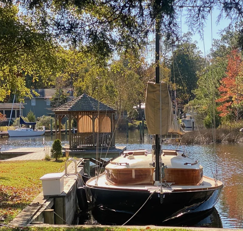 Slide: The Image of 37ft Catboat Yacht docked by a scenic riverside gazebo, surrounded by autumn foliage. - 5