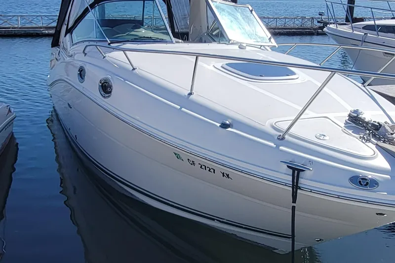 Slide: The Image of 2006 Sea Ray 260 Sundancer boat docked in marina, sleek white design. - 11