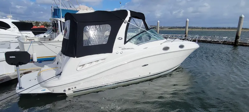 Slide: The Image of 2006 Sea Ray 260 Sundancer boat docked at marina, featuring black canopy and sleek design. - 3