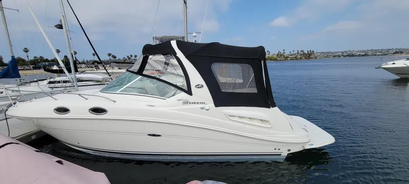 Slide: The Image of 2006 Sea Ray 260 Sundancer boat docked in a marina, featuring a black canopy. - 5