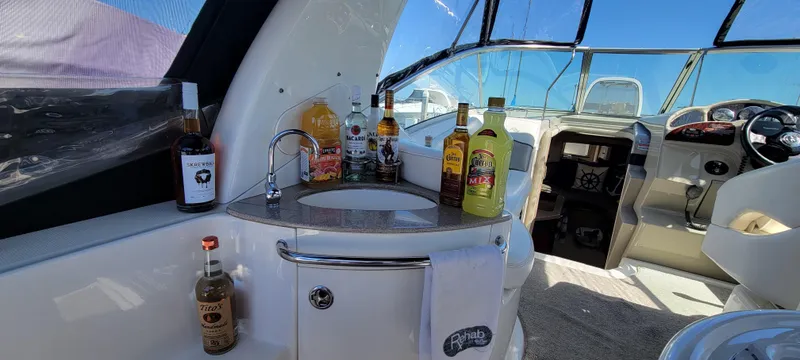 Slide: The Image of 2006 Sea Ray 260 Sundancer interior with bar setup, featuring various bottles and a sink. - 7