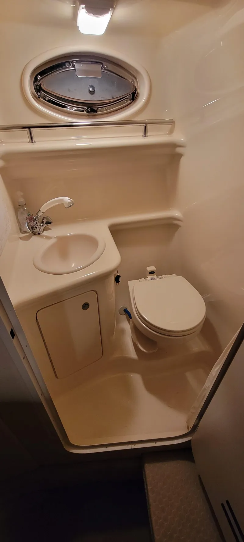 Slide: The Image of 2006 Sea Ray 260 Sundancer bathroom with sink, toilet, and porthole window. - 8