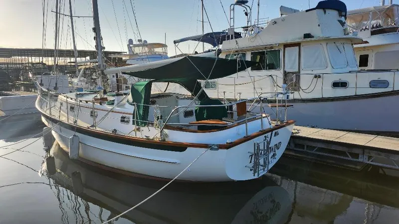 Slide: The Image of 1989 Cabo Rico 34 sailboat docked at marina, featuring classic design and green canopy. - 2
