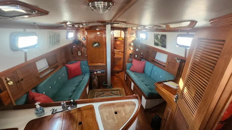 Slide: The Image of 1989 Cabo Rico 34 yacht interior with wood finish, teal seating, and red cushions. - 42