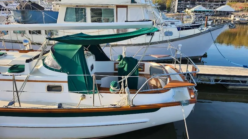 Slide: The Image of 1989 Cabo Rico 34 sailboat docked, featuring green canvas covers and classic wooden accents. - 5