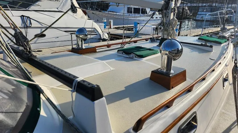 Slide: The Image of 1989 Cabo Rico 34 sailboat deck with polished fittings and moored yachts in background. - 7