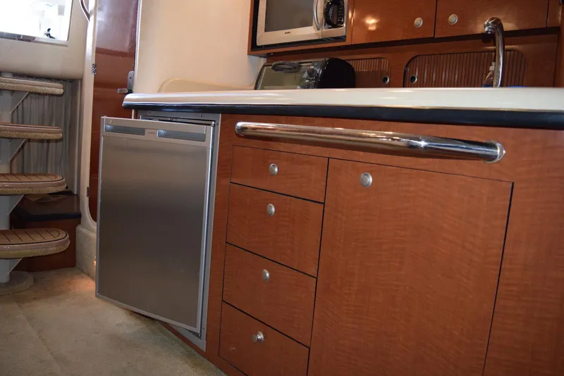 Slide: The Image of 2005 Sea Ray 340 Sundancer interior kitchen with wooden cabinets and stainless steel appliances. - 24