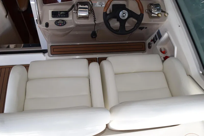 Slide: The Image of 2005 Sea Ray 340 Sundancer helm with dual white cushioned seats and wooden steering wheel. - 43