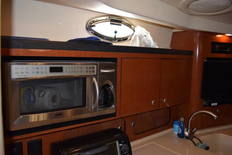 Slide: The Image of 2005 Sea Ray 340 Sundancer galley with microwave, sink, and wooden cabinetry. - 46