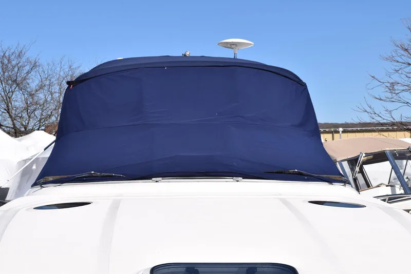 Slide: The Image of 2005 Sea Ray 340 Sundancer with blue canvas cover, docked under clear sky. - 48