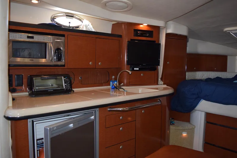 Slide: The Image of 2005 Sea Ray 340 Sundancer interior with kitchenette, featuring microwave, sink, and compact fridge. - 8