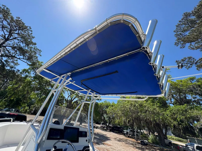 Slide: The Image of 2012 Edgewater 205CC boat with blue T-top under clear sky, surrounded by trees. - 12