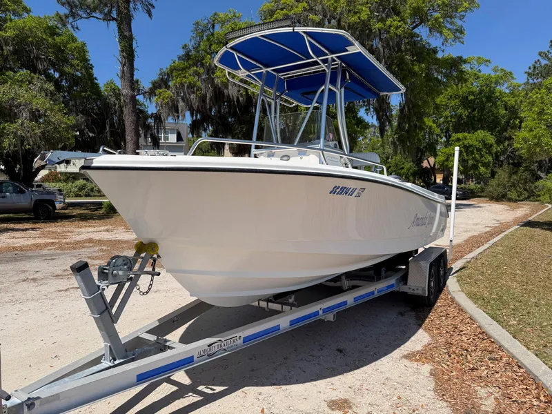 Slide: The Image of Edgewater 205CC 2012 boat on trailer with blue canopy, parked outdoors. - 2