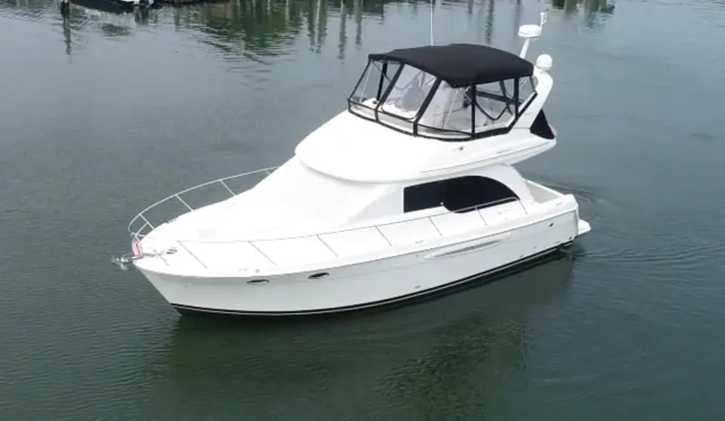 Slide: The Image of 2003 Meridian 381 Sedan yacht on calm water, featuring a sleek white design and black canopy. - 1