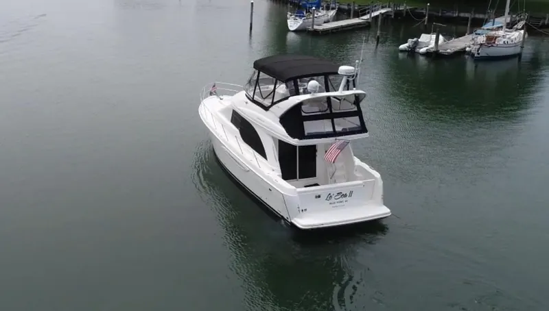 Slide: The Image of 2003 Meridian 381 Sedan boat cruising on calm water near a marina. - 2