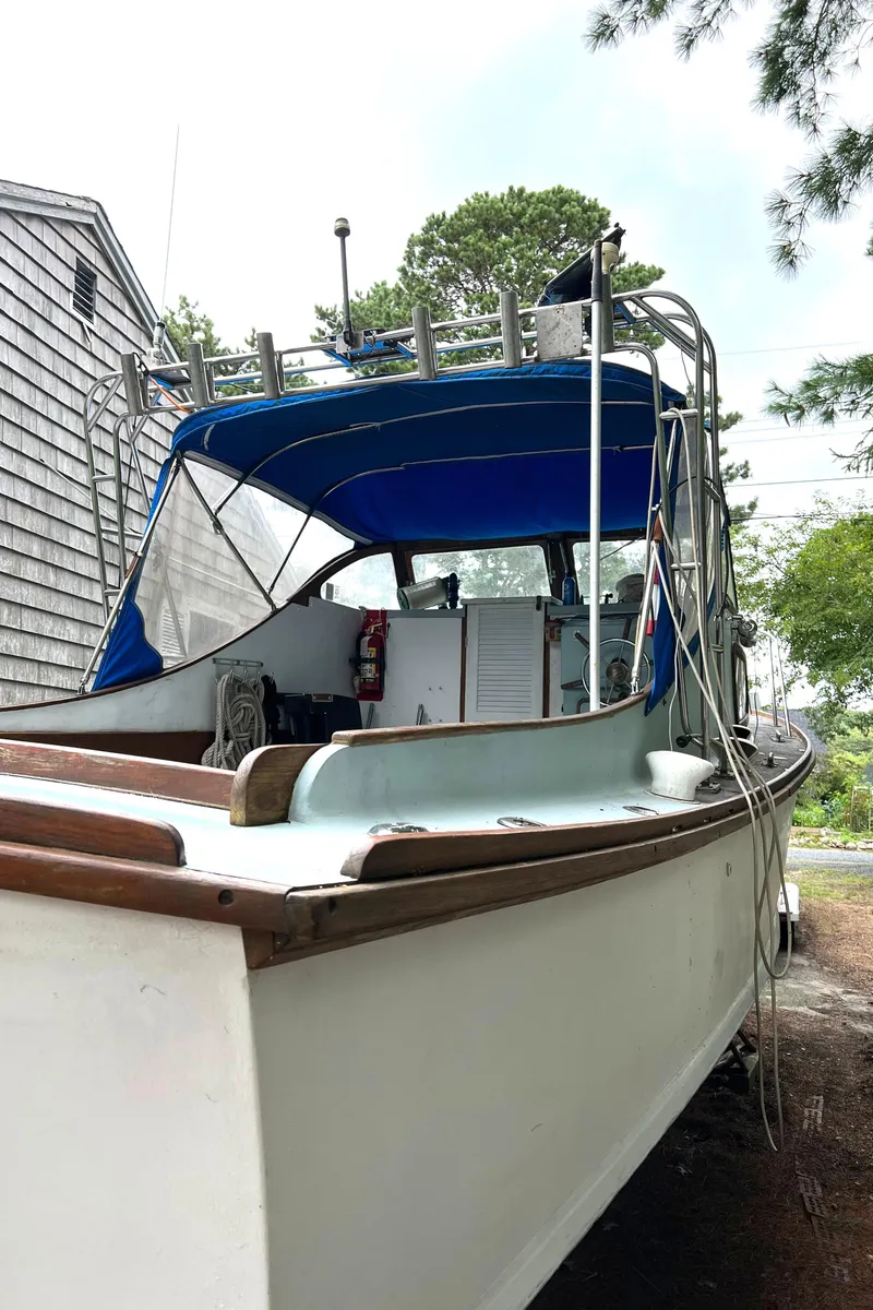 Slide: The Image of 1971 Dyer 29 Classic Downeast Bass Boat with blue canopy, docked near a wooden building. - 16