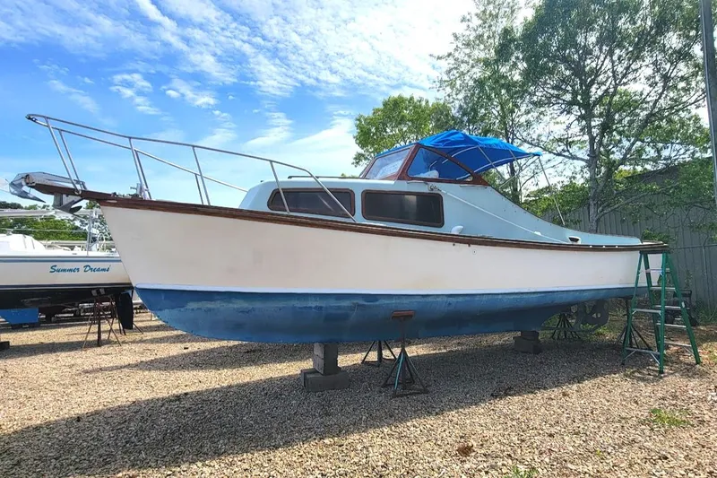 Slide: The Image of 1971 Dyer 29 classic downeast bass boat on land, blue and white hull, under clear sky. - 17