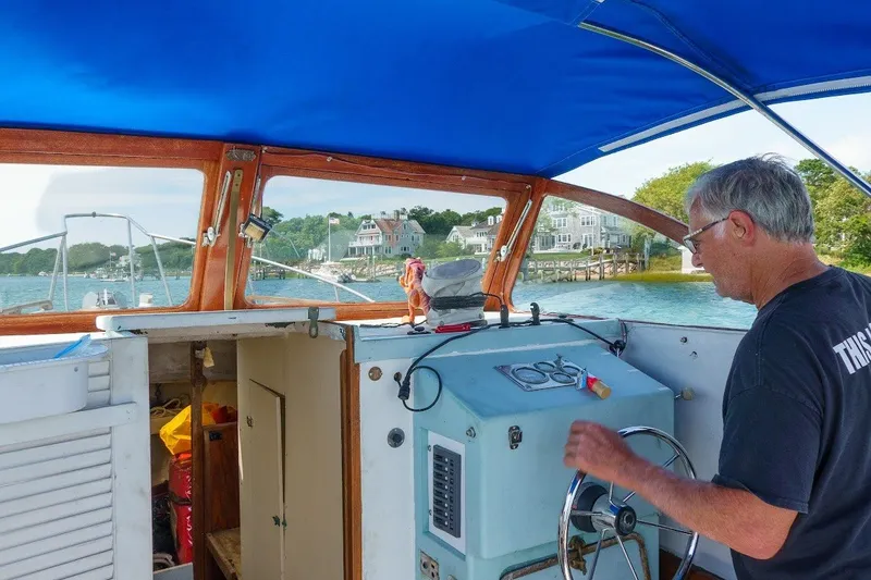 Slide: The Image of Man steering a 1971 Dyer 29 classic downeast bass boat under a blue canopy. - 1