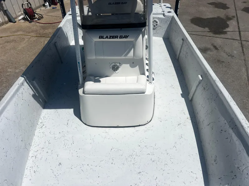 Slide: The Image of 2012 Blazer Bay 2400 boat on trailer with Yamaha outboard motor, parked outside a warehouse. - 2
