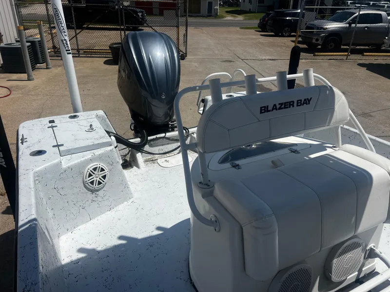 Slide: The Image of 2012 Blazer Bay 2400 boat with T-top, parked outdoors under cloudy sky. - 4
