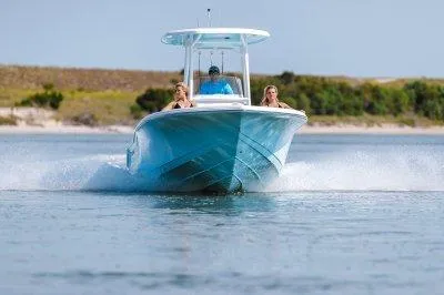 Slide: The Image of 2026 Tidewater 210CC boat cruising on water with passengers, scenic background. - 2