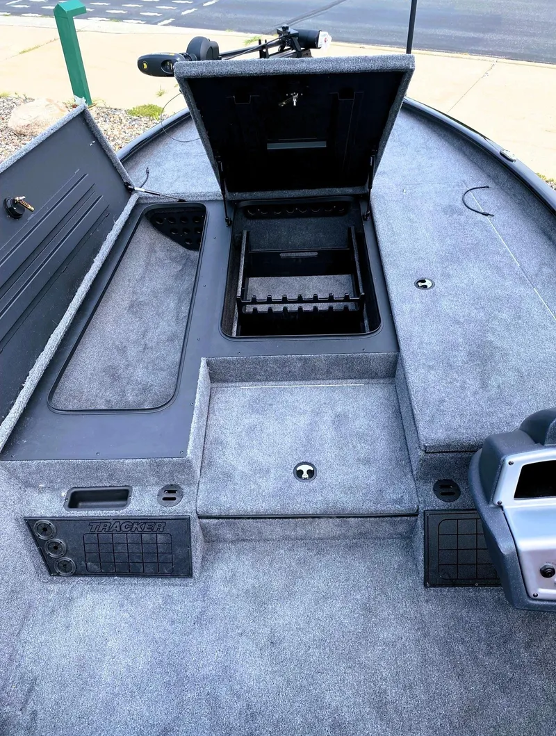 Slide: The Image of 2025 Tracker Savage 215 boat interior with open storage compartments and carpeted flooring. - 6