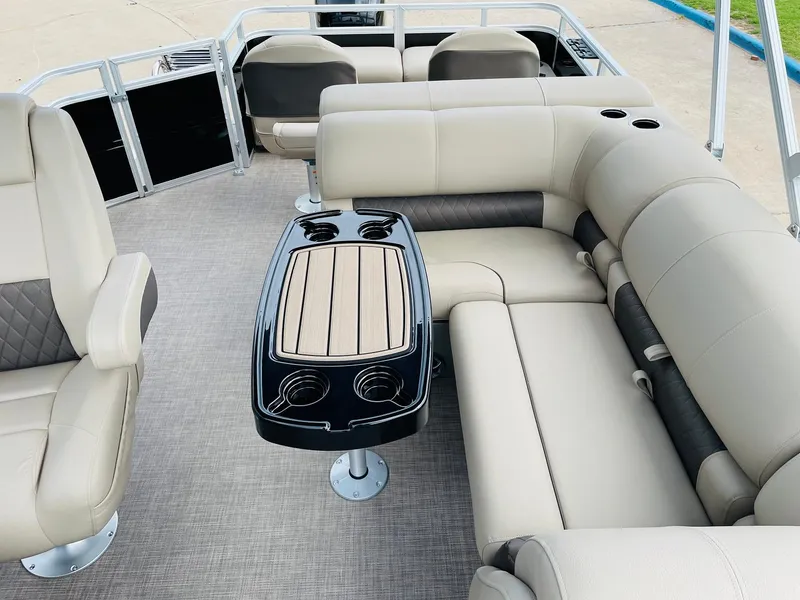 Slide: The Image of 2025 Sun Tracker SportFish 22 DLX pontoon boat interior with beige seating and central table. - 26