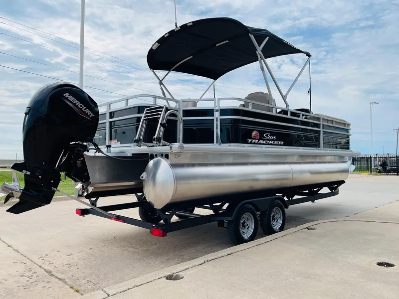 Slide: The Image of 2025 Sun Tracker SportFish 22 DLX pontoon boat on trailer, featuring a Mercury outboard motor. - 5
