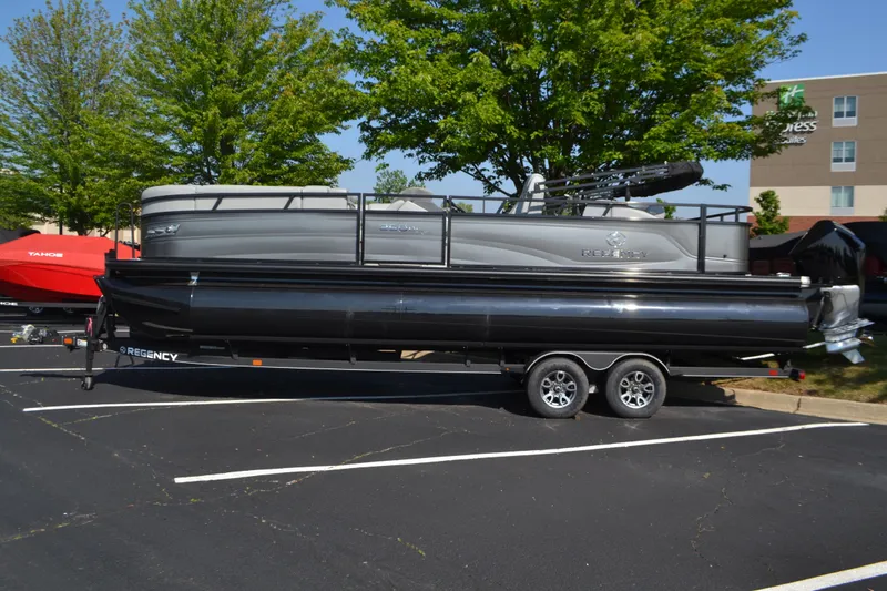 Slide: The Image of 2025 Regency 250 DL3 pontoon boat on trailer in parking lot. - 0