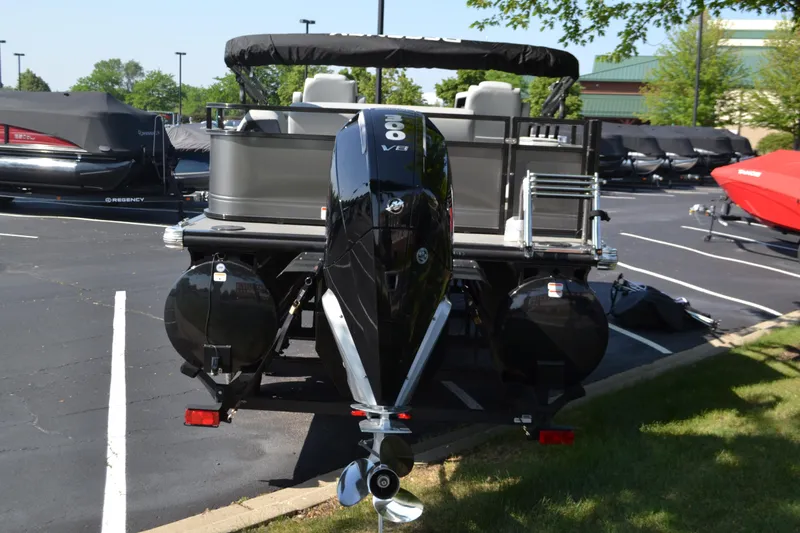 Slide: The Image of 2025 Regency 250 DL3 pontoon boat with powerful outboard motor in a parking lot. - 2