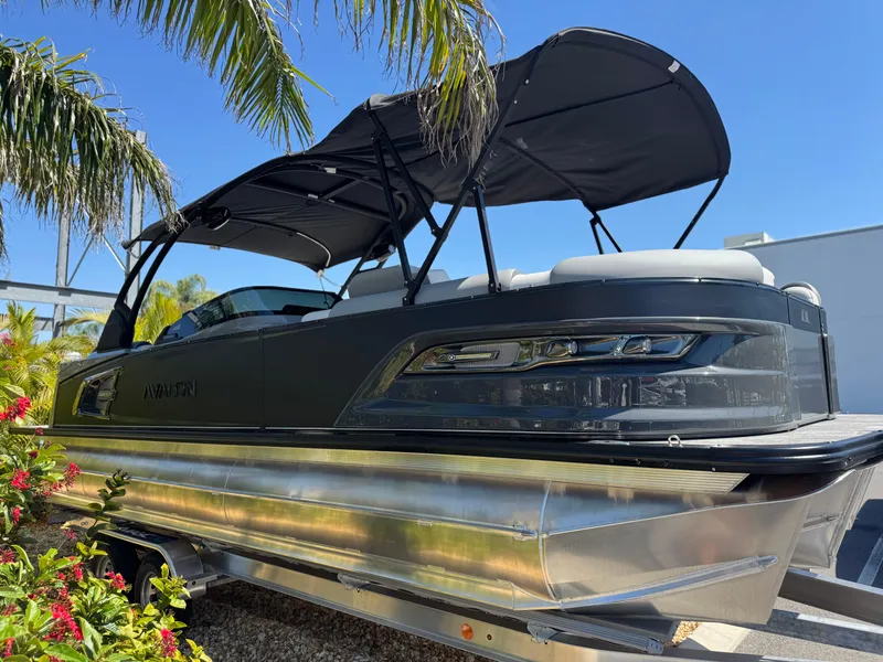 Slide: The Image of 2025 Avalon Excalibur 27' boat with canopy, displayed outdoors under palm trees. - 7