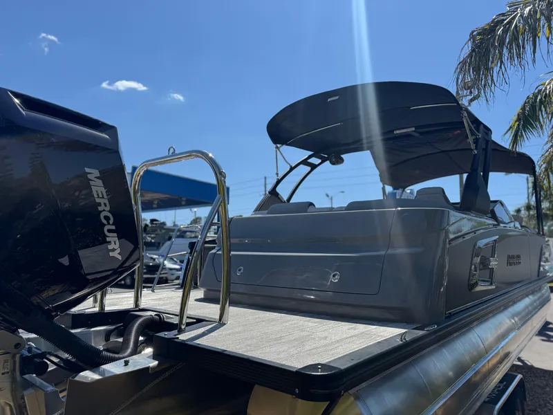 Slide: The Image of 2025 Avalon Excalibur 27' boat with Mercury engine, docked under clear blue sky. - 9