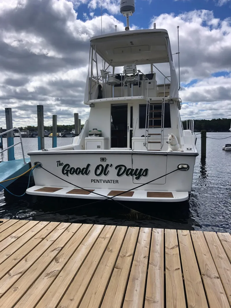 Slide: The Image of 1990 Tiara Yachts 4300 Convertible docked, named "The Good Ol' Days," under a partly cloudy sky. - 2