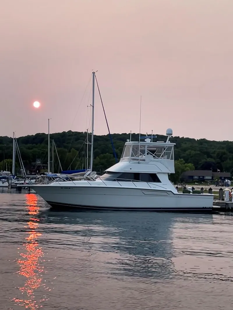 Slide: The Image of 1990 Tiara Yachts 4300 Convertible docked at sunset, reflecting on calm water. - 7