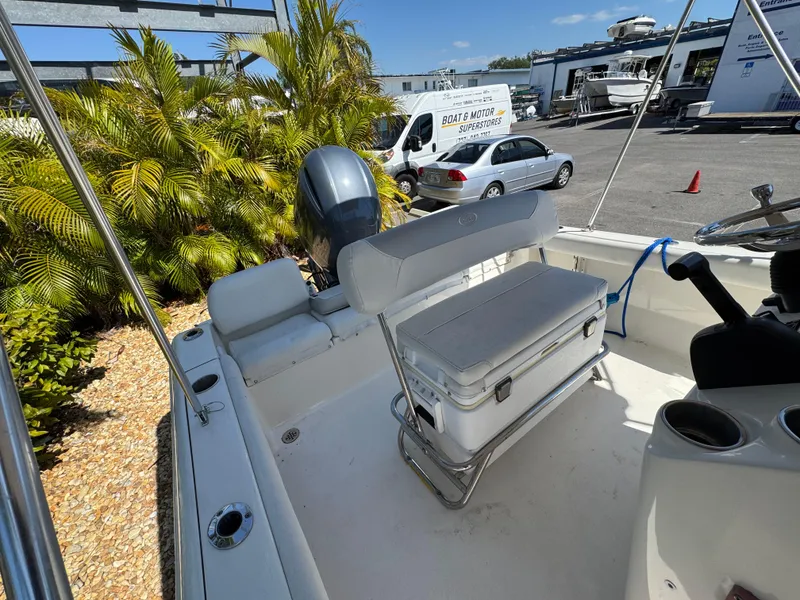 Slide: The Image of 2022 Key West 189 FS boat interior with seating and motor, parked near tropical plants. - 19
