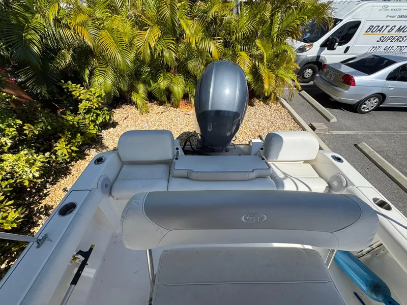 Slide: The Image of 2022 Key West 189 FS boat interior with outboard motor, parked near lush greenery. - 20