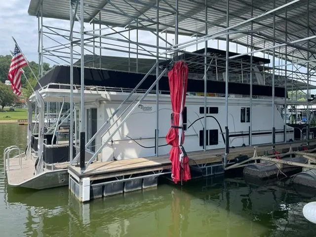 Slide: The Image of 2016 Sunstar 16x58 houseboat docked under a covered marina with an American flag. - 17