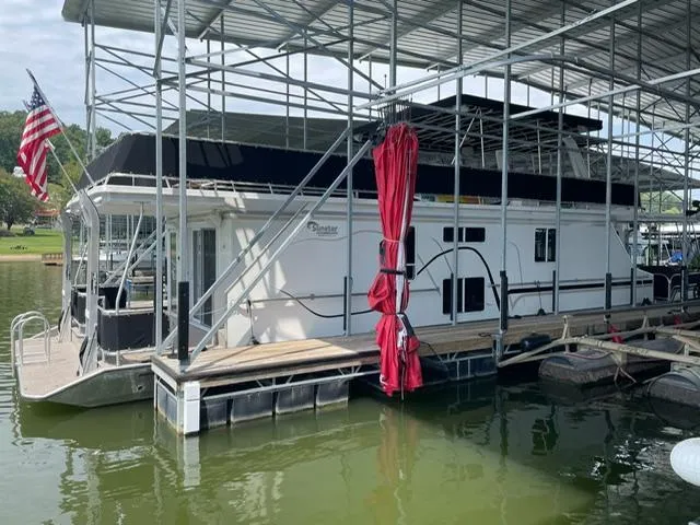 Slide: The Image of Houseboat docked under shelter, Sunstar 16x58, 2016 model, with American flag and red curtain. - 18