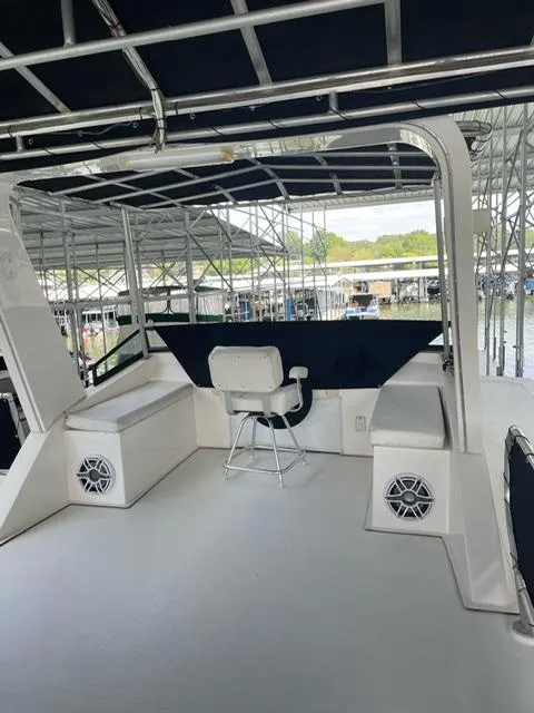 Slide: The Image of 2016 Sunstar 16x58 houseboat interior with seating and speakers at a marina. - 24