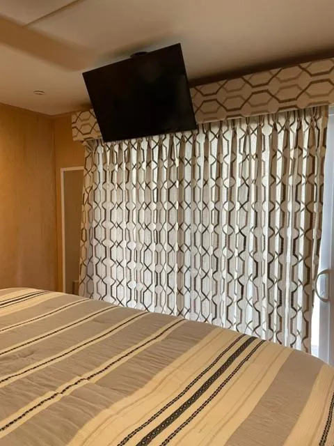 Slide: The Image of Bedroom interior of 2016 Sunstar 16x58 with patterned curtains and mounted TV. - 35