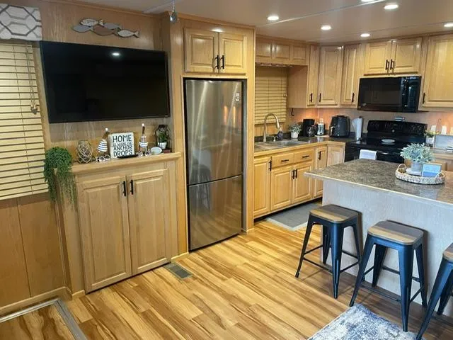 Slide: The Image of Modern kitchen interior in a 2016 Sunstar 16x58 houseboat with wooden cabinets and stainless steel appliances. - 7