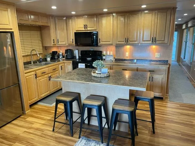 Slide: The Image of Modern kitchen in a 2016 Sunstar 16x58 houseboat with wooden cabinets and island seating. - 8