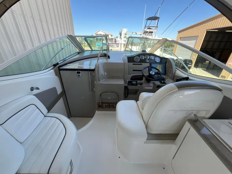 Slide: The Image of 2006 Sea Ray 290 Sundancer cockpit with steering wheel and seating, docked near marina. - 15