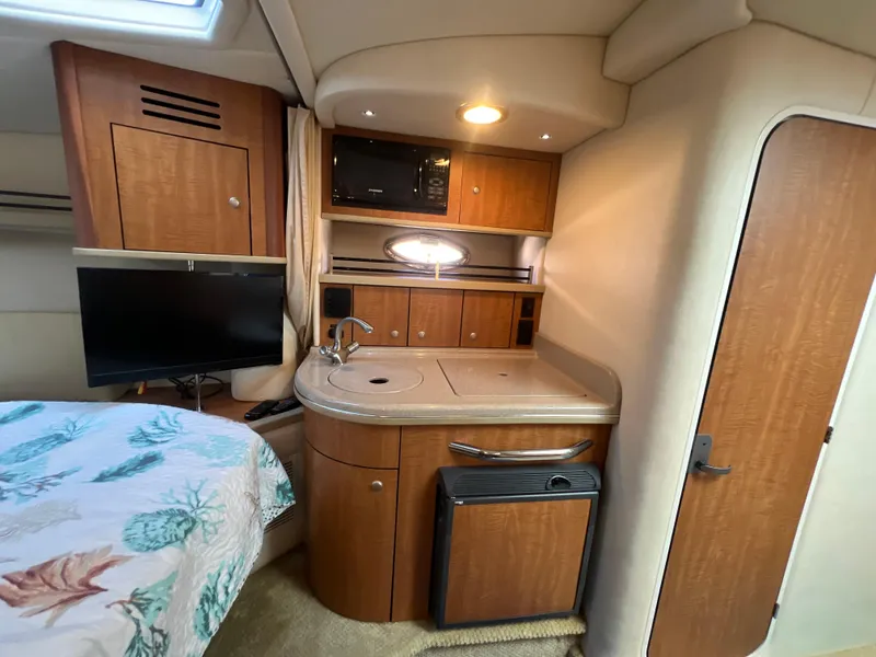 Slide: The Image of 2006 Sea Ray 290 Sundancer cabin with kitchenette, TV, and bed. - 29